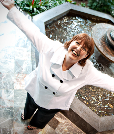 denise reed in a white suite in front of a fountain