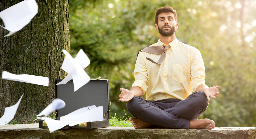 business man meditating while his papers fly away