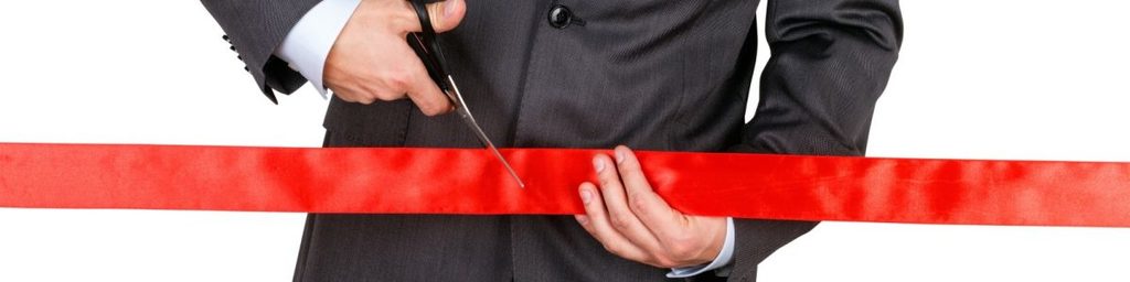 professional in a suit cutting a red ribbon